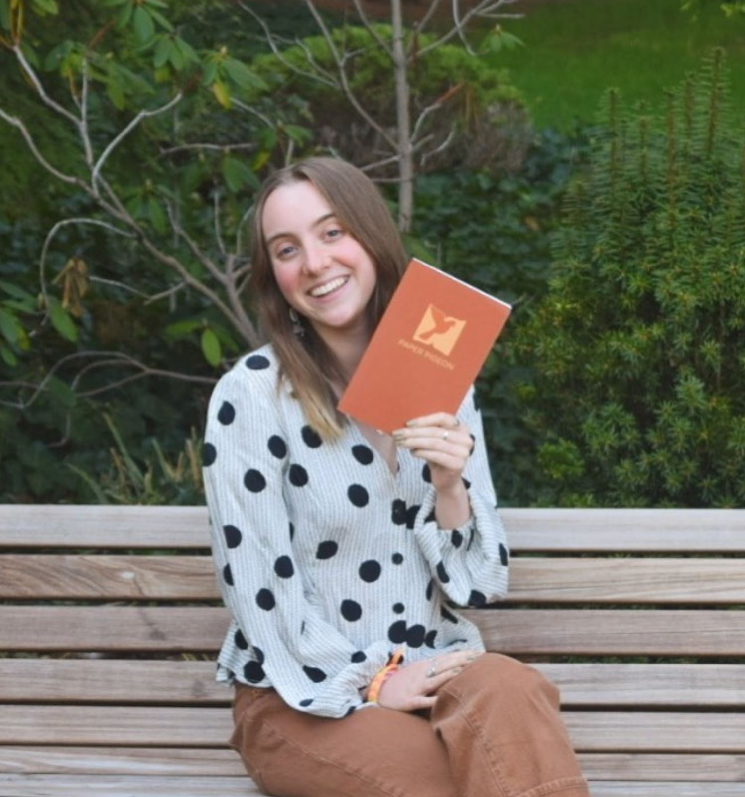 woman sitting on the bench holding a paper pigeon book Gorham Printing